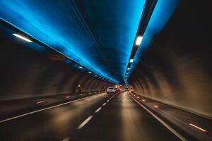 Long exposure capture of cars driving through a modern tunnel with blue lighting, showcasing speed and motion.