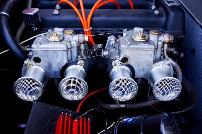 Detailed view of dual carburetors in an engine bay with chrome finishes, highlighting classic automotive engineering.