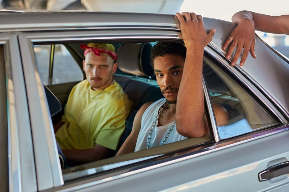 Two young men sitting in a car looking out the window, capturing an urban lifestyle moment with vibrant city vibes.