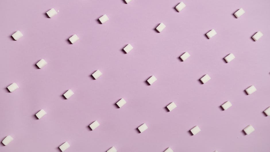 Geometric arrangement of white sugar cubes on a pastel pink surface.