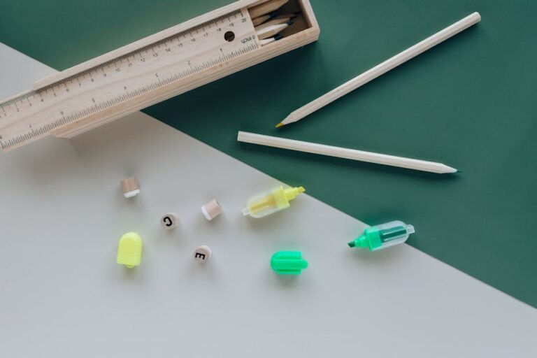 A minimalist flat lay of pencils, a ruler, and markers on a geometric green and white background.