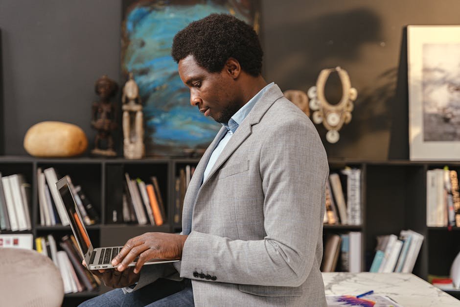 Side view of a man using a laptop while sitting in a modern library office.