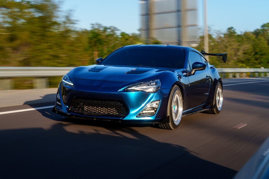 Dynamic shot of a blue sports car speeding on an open highway, capturing motion and power.