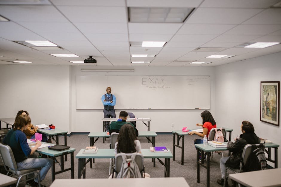 A classroom setting with a teacher proctoring an exam, students focused on their tests.