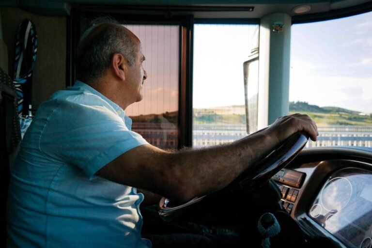 An elderly man driving at sunset, enjoying the view as he navigates the road.