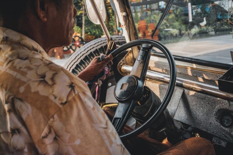 Close-up of a man driving a vintage car with focus on the dashboard and steering wheel.