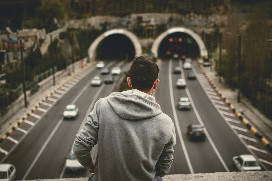 A man in a hoodie looks over traffic entering tunnels in Tehran, Iran.